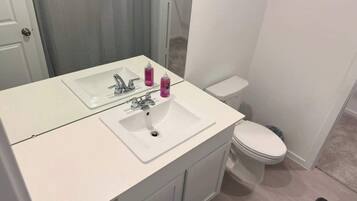 A bathroom with a white sink, mirror, and toilet.