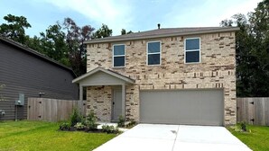 A two-story house with a garage, a front porch, and a well-maintained lawn. - @ Marbella Lane - Tranquil Escape in Texas Pines (Splendora)