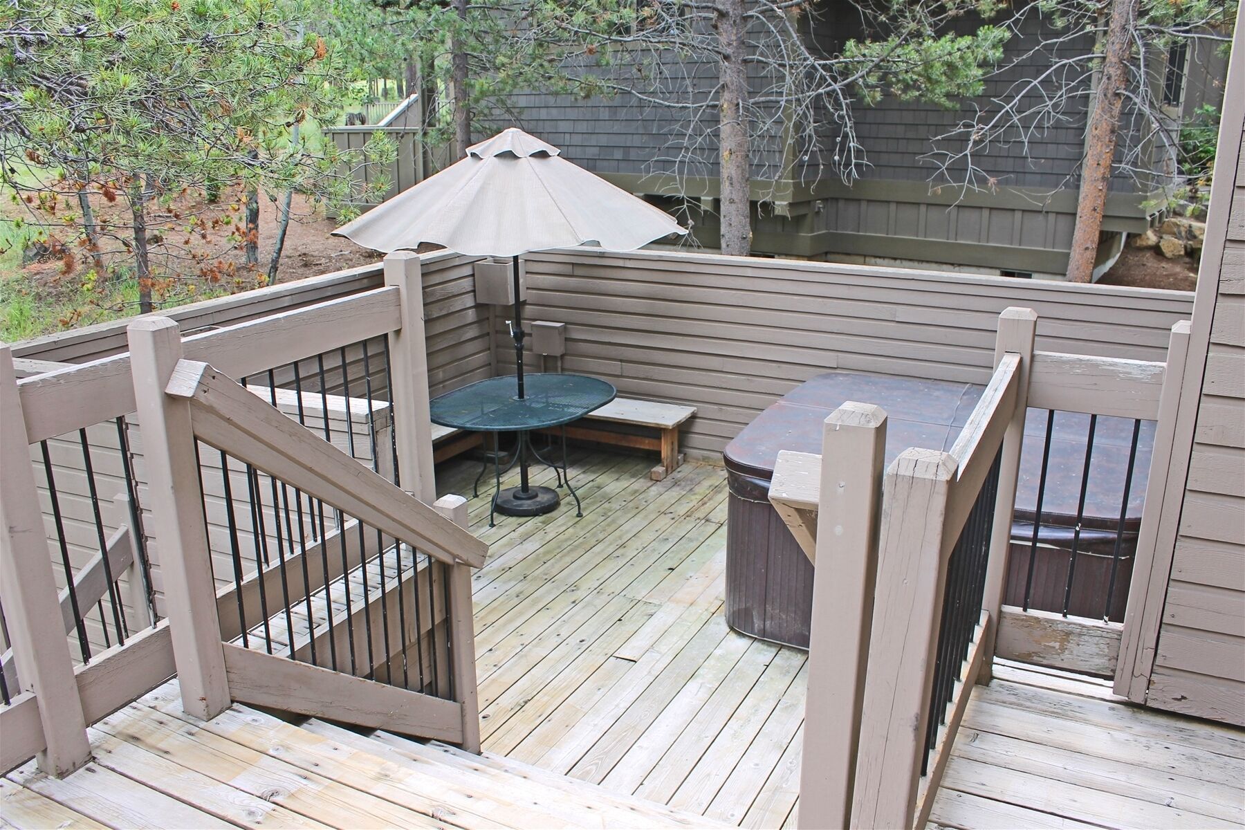 A wooden deck with a table and chairs, a covered seating area, and a wooden fence.