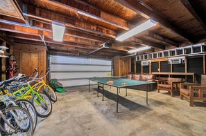 Un grand espace intérieur aménagé avec une table de ping-pong, des bancs en bois et des vélos.
