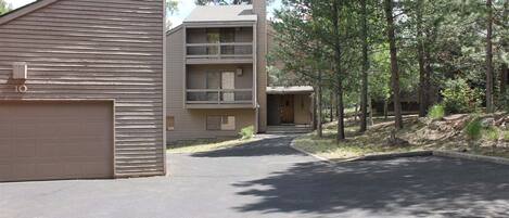 Ein zweistöckiges Gebäude mit Garage, einem Balkon im zweiten Stock und einer Auffahrt zum Eingang.