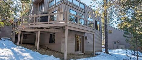 A multi-story house with a balcony, a covered entryway, and a snow-covered ground.