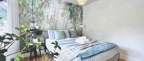 A bedroom with a bed, a hanging light fixture, and a wall with a textured pattern.