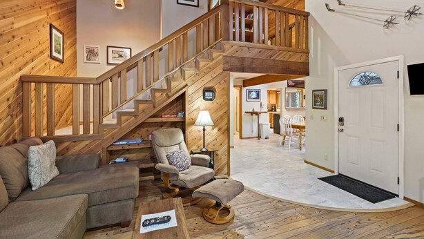 Un interior de madera con una escalera, un sofá, una silla y un comedor.
