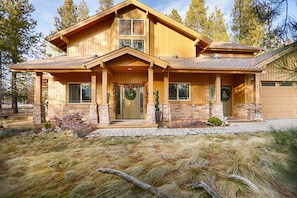 Ein zweistöckiges Holzhaus mit Stein Fundament, einer Veranda und einer Garage.