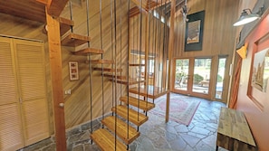 Eine moderne Holztreppe führt zu einem Bereich mit Steinböden und Blick ins Freie.