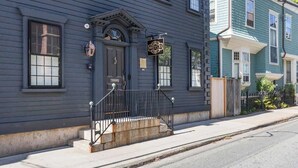 A two-story building with a dark blue exterior, a black front door, and a sign that reads "ROYCE." - Regatta Suite at The Royce Refined Newport Charm (Newport)