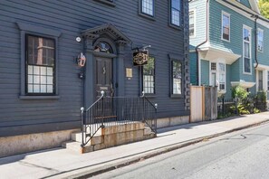 A two-story building with a dark blue exterior, a black front door, and a sign that reads "ROYCE." - Regatta Suite at The Royce Refined Newport Charm (Newport)