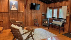 Interior acogedor de una cabaña de madera con chimenea, televisor y muebles rústicos.