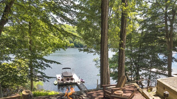 A lakeside campsite with a fire pit, chairs, and a dock with a boat. - Lake Wallenpaupack Lakefront Private Boat Slip (Greentown)