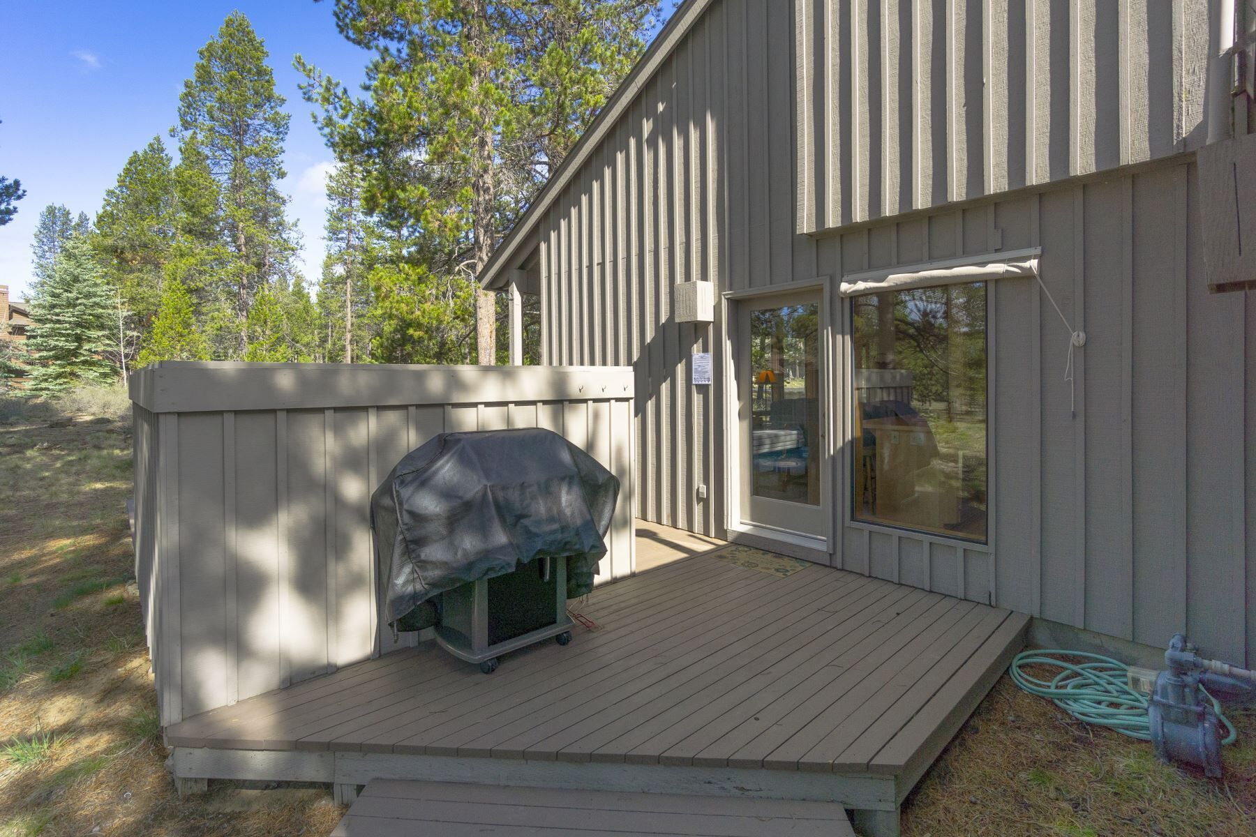 A wooden deck with a covered grill and a sliding glass door.
