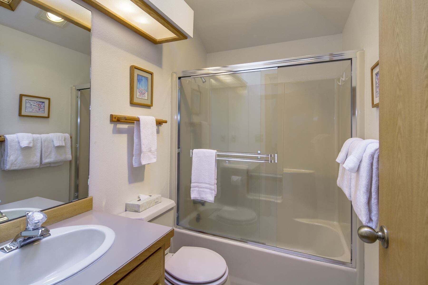 A bathroom with a glass-enclosed shower, a sink, and a toilet.