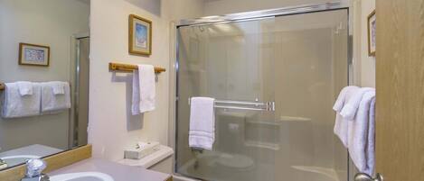 A bathroom with a glass-enclosed shower, a sink, and a toilet.