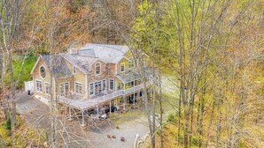 Une grande maison à deux étages, dotée d’un toit à pignon bien visible et d’un porche abrité.