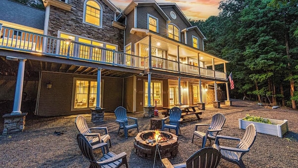 Une maison à deux étages dotée d’un patio couvert, d’un espace salon extérieur et d’un foyer.