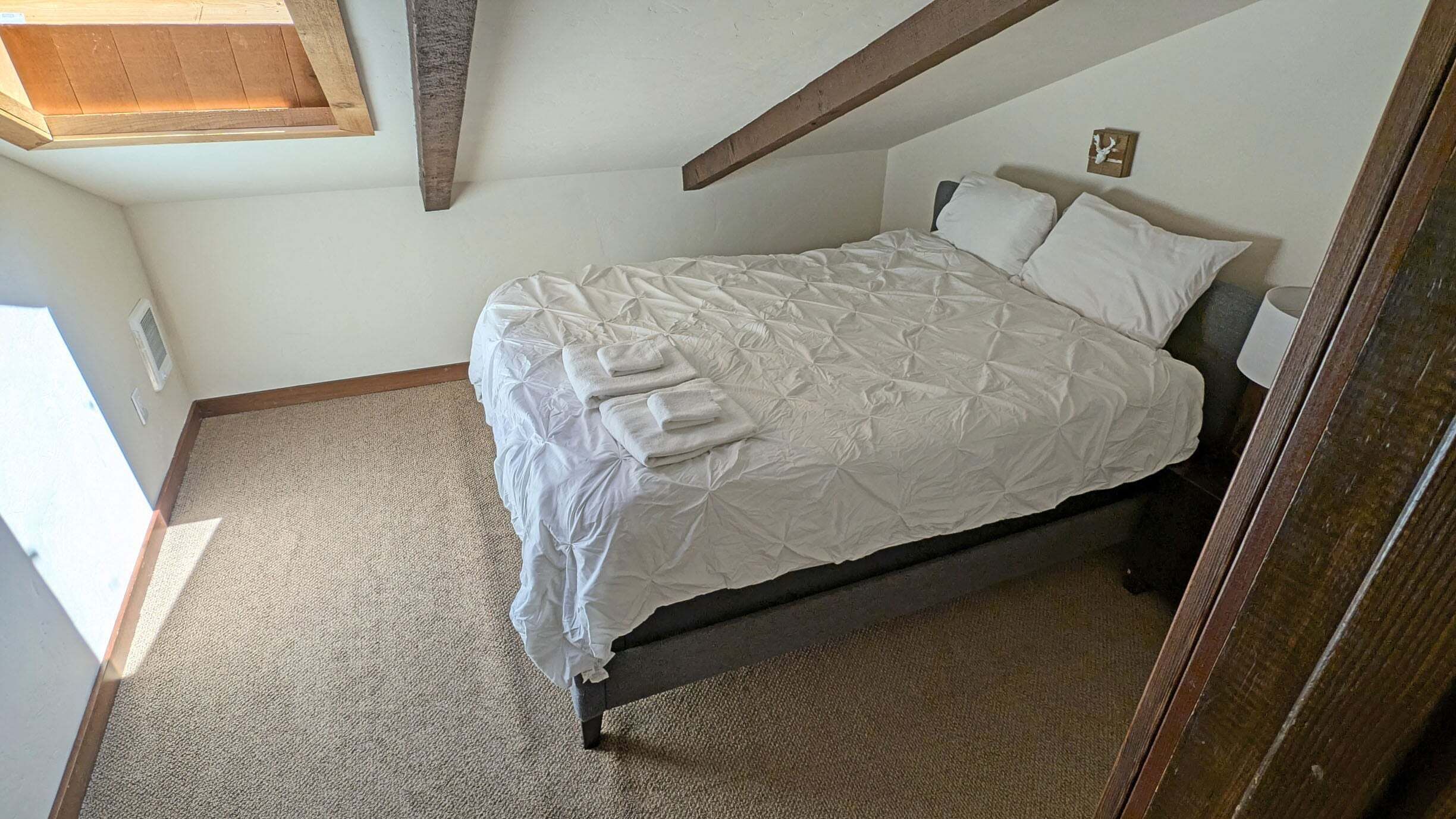 Een slaapkamer met een bed, kussens en een nachtkastje.