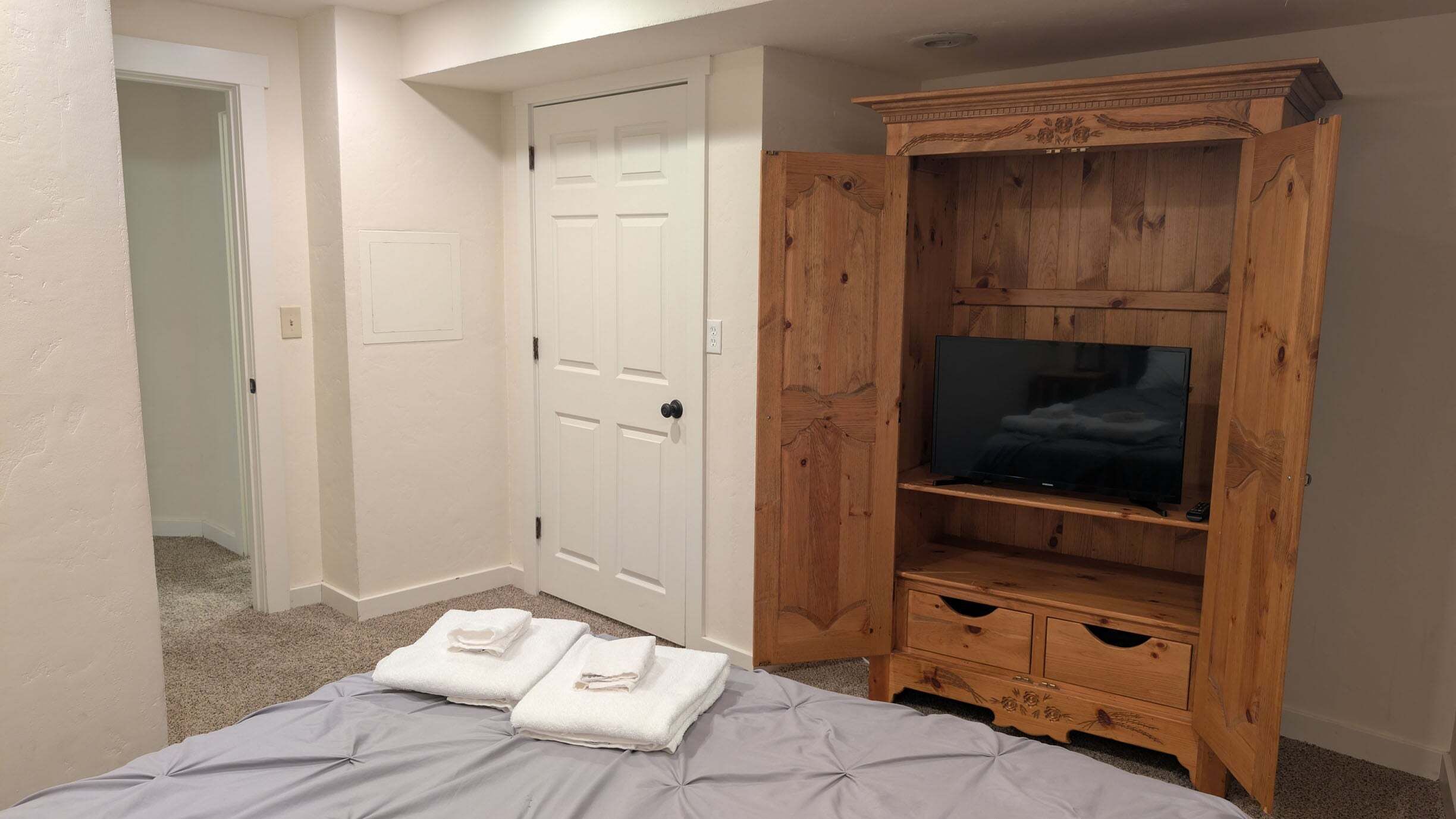 Ein Schlafzimmer mit einem Bett, einem Holz-Fernsehschrank und einer weißen Tür.