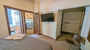 A bedroom with a bed, a TV, a chair, and a wardrobe. - Indian 3 (Bend)