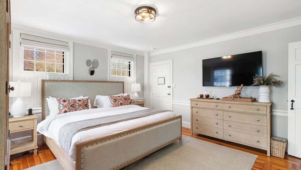 A bedroom with a large bed, a dresser, a TV, and a ceiling light. - Driftwood Suite - Luxury Retreat in Newport (Newport)