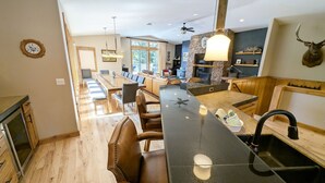 A spacious kitchen with a long island, wooden flooring, and a stone accent wall. - Yellow Pine 32 (Bend)