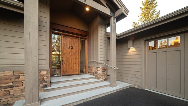 A house with a wooden front door, stone accents, and a garage door. - Yellow Pine 32 (Bend)