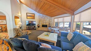 A cozy living room with a stone wall, a flat-screen TV, and a large window. - Grouse 4 (Bend)