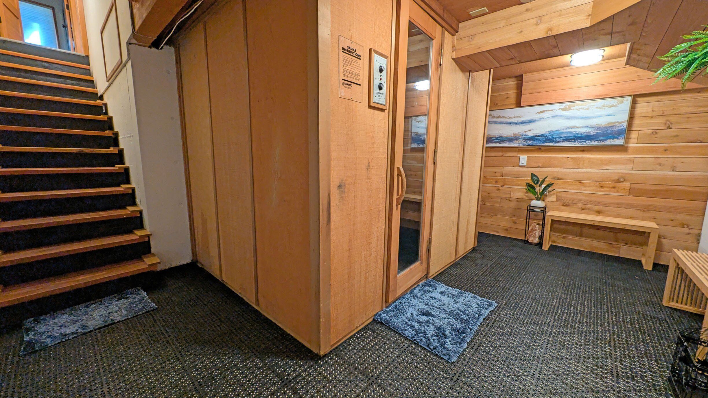 Una sauna con pareti in legno, una panca, un tavolino e un quadro appeso al muro.