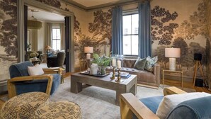 A spacious living room with a large coffee table, sofas, and a chandelier. - The Whale Suite Historic Coastal Luxury Newport (Newport)