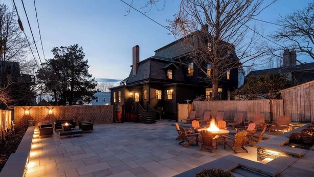 A backyard patio with a fire pit, outdoor furniture, and a brick wall. - The Whale Suite Historic Coastal Luxury Newport (Newport)