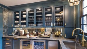 A kitchen with dark blue cabinetry, a stainless steel refrigerator, and a built-in wine cooler. - The Whale Suite Historic Coastal Luxury Newport (Newport)
