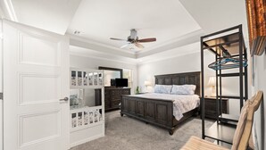 Une chambre avec un lit superposé, un bureau avec une chaise, une armoire et un ventilateur de plafond.