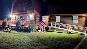 Ein Blockhaus mit Veranda, Treppe und gut beleuchtetem Eingangsbereich.