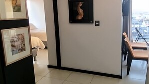 Una habitación de hotel con una cama, un área de comedor con sillas y cuadros en la pared.