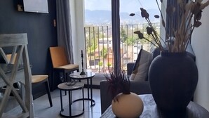 Una sala de estar moderna con un ventanal grande, un televisor de pantalla plana, una mesa de comedor con sillas y un sofá.