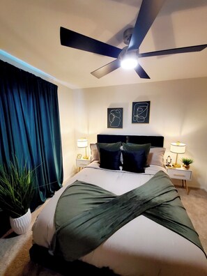 A bedroom with a bed, two bedside tables with lamps, a ceiling fan, and two wall art pieces. - GOLDEN RAVEN House (Indio)