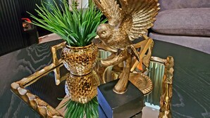 A modern living room with a glass coffee table, a potted plant, and decorative golden items. - GOLDEN RAVEN House (Indio)