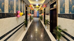 A hallway with marble walls, a black marble floor, and potted plants. - Hotel Luxury Palace Vrindavan (Vrindavan)