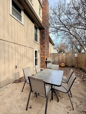 An outdoor patio with a table and chairs, a barbecue grill, and a wooden fence. - Cozy Guest Suite near Downtown Lee's Summit (Lee's Summit)