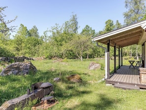 A covered outdoor area with a grill, picnic table, and benches.