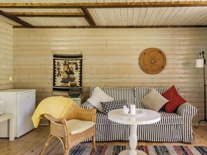 A cozy room with a striped sofa, a wicker chair, a small white table, and a woven wall hanging.