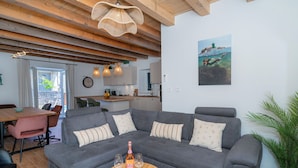 A cozy living room with a grey sectional sofa, a wooden coffee table, and a dining area with a pink chair. - Vacation home Nina by Interhome (Brač/Donji Humac)