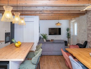 A modern kitchen with wooden cabinets, a built-in oven, and a dining area with a wooden table and chairs.