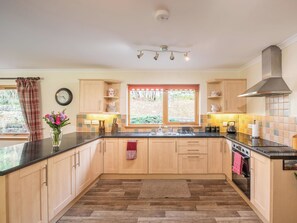 Una cucina moderna con mobili in legno, un piano di lavoro nero, una finestra con vista e un piano cottura integrato.