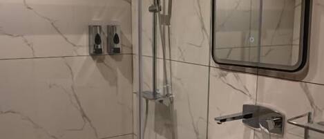 A modern bathroom with a glass-enclosed shower, a white sink, and a mirror.