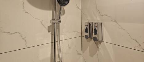 Ein modernes Badezimmer mit Dusche, einer Handbrause und einer fest installierten Bedienkonsole.