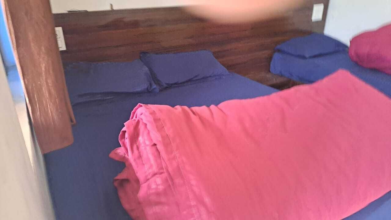 Una habitación con cabecera de madera, una cama con manta rosa y otra cama con manta azul.