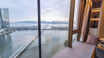 Habitación de hotel en un edificio alto, con vista a un horizonte urbano y un puente sobre el agua.