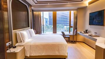 Habitación de hotel con una cama grande, un escritorio con una silla, un televisor y vistas a la ciudad.