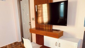 A modern room with a wooden desk, a white chair, a flat-screen TV, and a white cabinet. - Hotel Sea Inn Saint Martin (Saint Martin's Island)