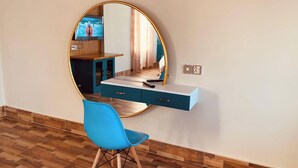 A room with a round mirror, a blue chair, a desk with drawers, and a wooden floor. - Hotel Sea Inn Saint Martin (Saint Martin's Island)